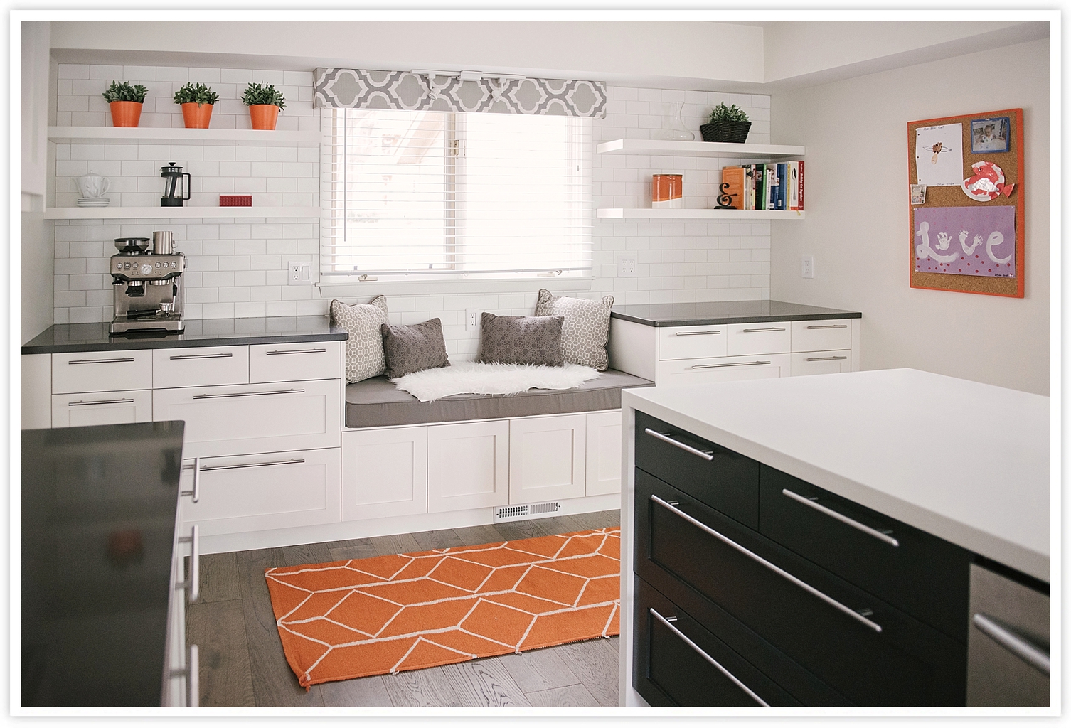 After: Clean white modern black and white IKEA kitchen with Semihandmade cabinet faces, CB2 bar stools, open shelving, a window seat, dorian white waterfall countertops, and a Tamburo hood vent (with orange accents)