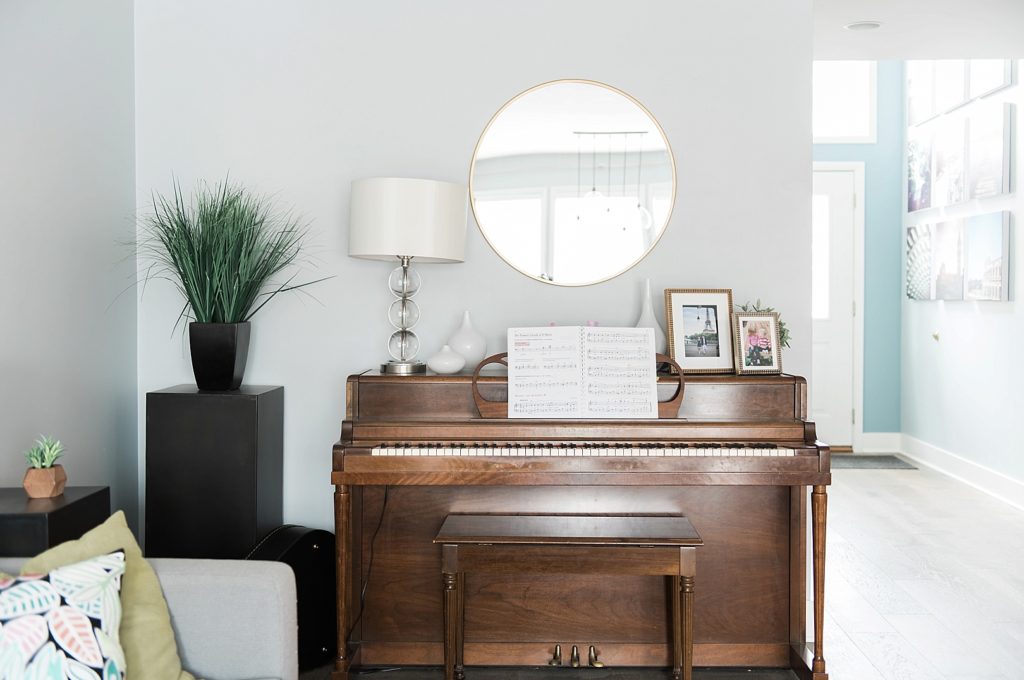 Piano with round mirror and small framed photos