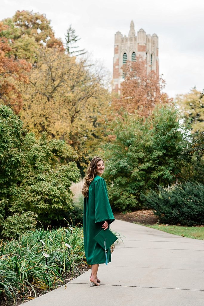 Ideas and locations for a Michigan State University fall senior photo session on north campus by Allie Siarto Photography, East Lansing Photographers. A photo of an MSU senior walking down a sidewalk with Beaumont Tower in the background.