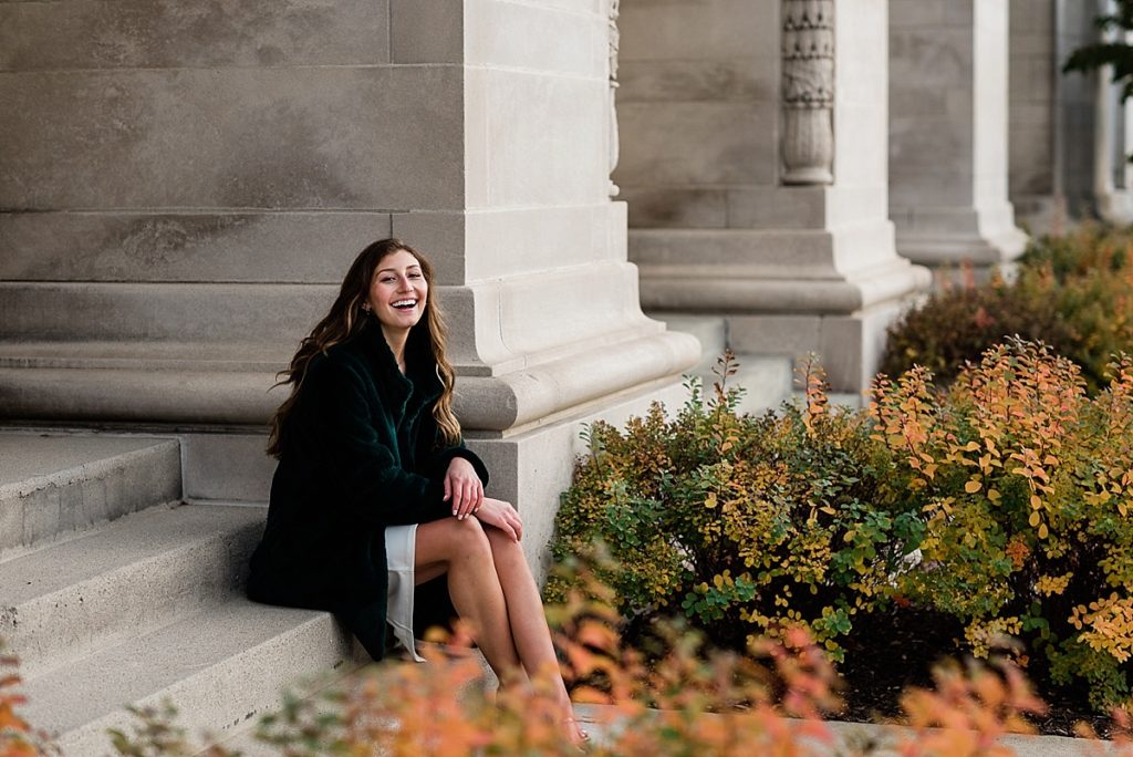 Ideas and locations for a Michigan State University fall senior photo session on north campus by Allie Siarto Photography, East Lansing Photographers. A photo of an MSU senior sitting on stone steps showing classic architecture on MSU's campus.