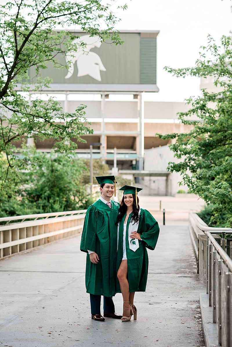 Michigan State Senior Pictures with a couple in cap and gown on MSU's campus on the bridge behind the library by Spartan Stadium, by Allie Siarto & Co. Photography, MSU graduation photographers