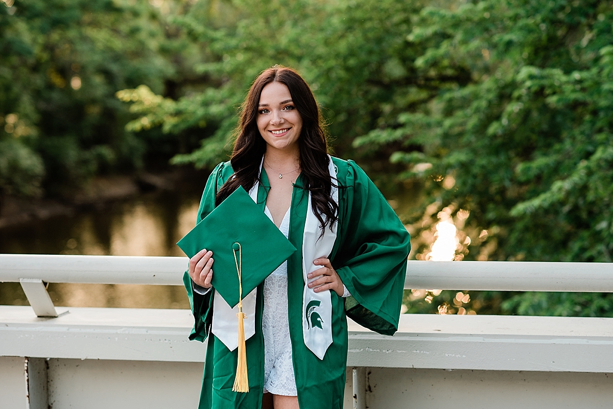 Michigan State Senior Pictures with cap and gown on MSU's campus on the bridge by the library and Spartan Stadium overlooking the Red Cedar River, by Allie Siarto & Co. Photography, MSU graduation photographers