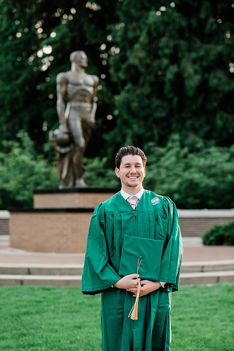 Michigan State Senior Pictures with a guy in a cap and gown on MSU's campus in front of the Sparty Statue, by Allie Siarto & Co. Photography, MSU graduation photographers