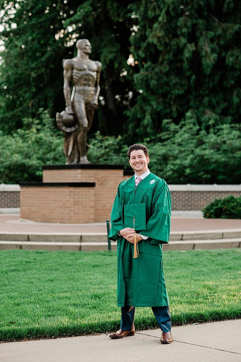 Michigan State Senior Pictures with a guy in a cap and gown on MSU's campus in front of the Sparty statue, by Allie Siarto & Co. Photography, MSU graduation photographers