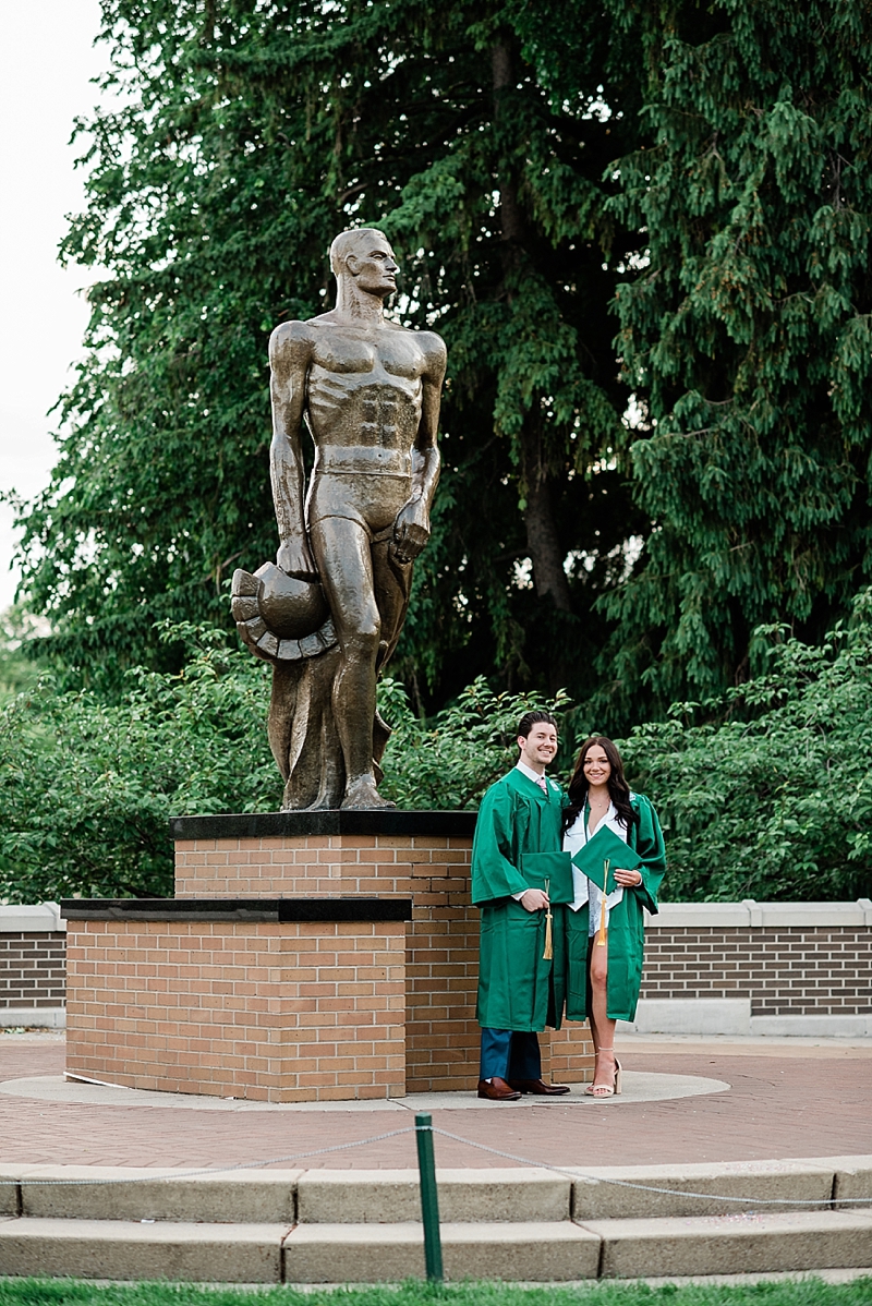 Michigan State Senior Pictures with a couple in cap and gown on MSU's campus in front of the Sparty statue, by Allie Siarto & Co. Photography, MSU graduation photographers