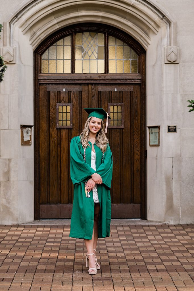 Michigan State University senior photography ideas with roommates on campus in white dresses and cap and gown in front of the door at Beaumont Tower, by Allie Siarto & Co, senior photographers in East Lansing, Michigan