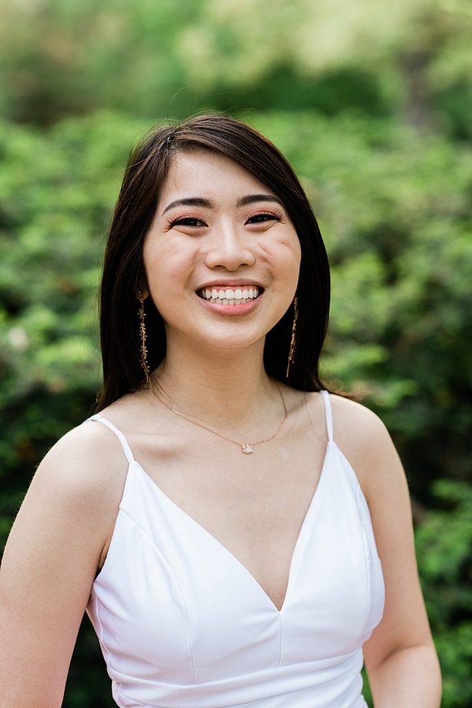 Michigan State Senior Graduation Pictures in a white dress on campus; grad photos in front of greenery near Beaumont Tower by Allie Siarto & Co. Photography