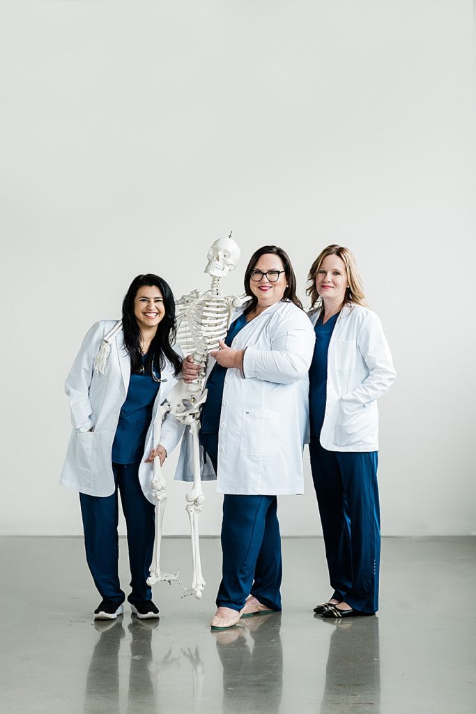 Studio branding headshots with three nurses with a skeleton on a white backdrop by Allie & Co. Photography in Lansing, Michigan