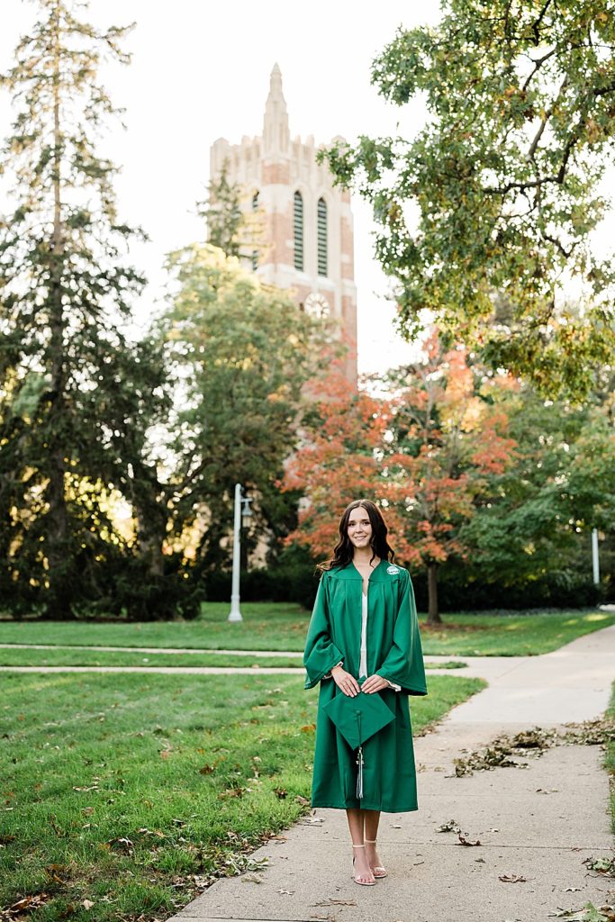 MSU graduation pictures on north campus in the fall with a white dress and grad gown with Beaumont Tower in the background by Allie & Co. Photography, East Lansing photographers