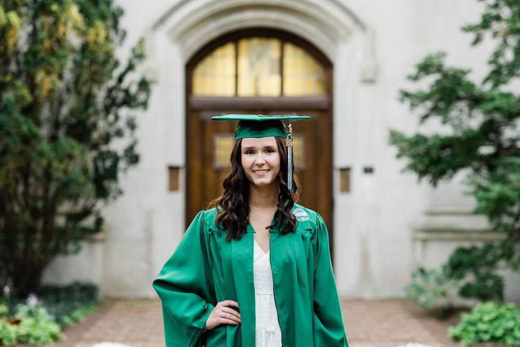 Michigan State graduation pictures on north campus in the fall with a white dress, cap and gown, and the Beaumont Tower door in the background by Allie & Co. Photography, East Lansing photographers