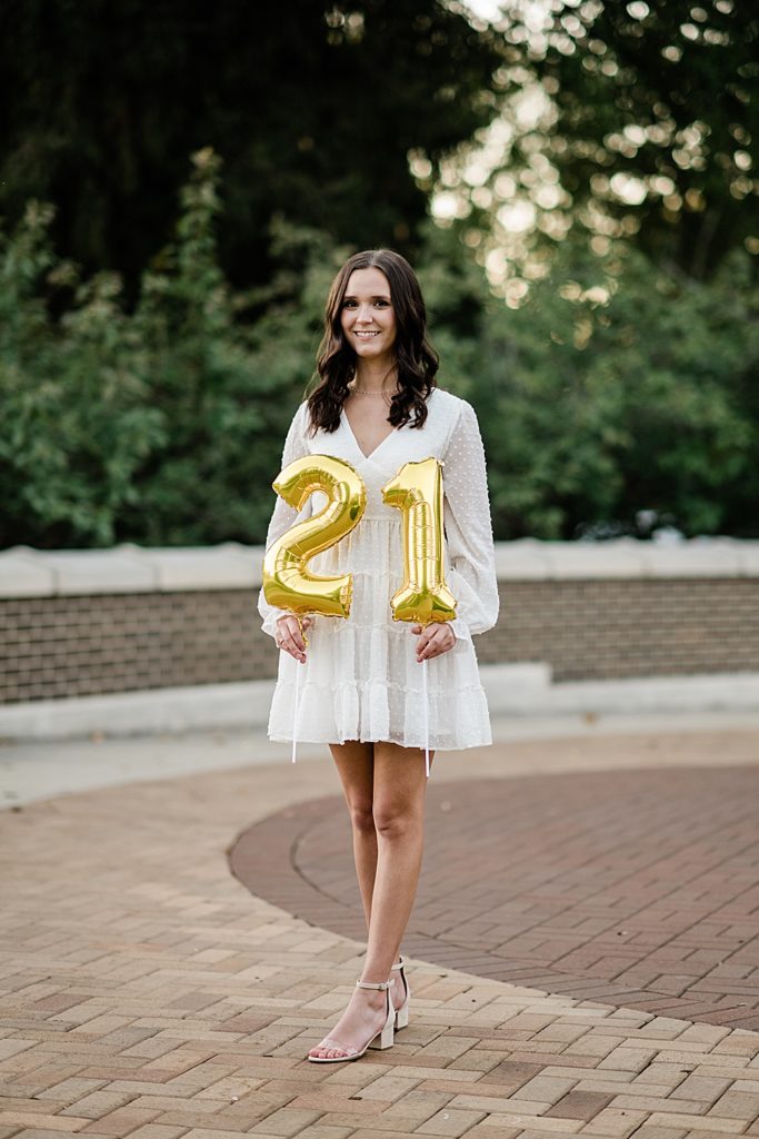 Michigan State graduation pictures on north campus in the fall with a white dress and balloons that say 21 for a 21st birthday by Allie & Co. Photography, East Lansing photographers