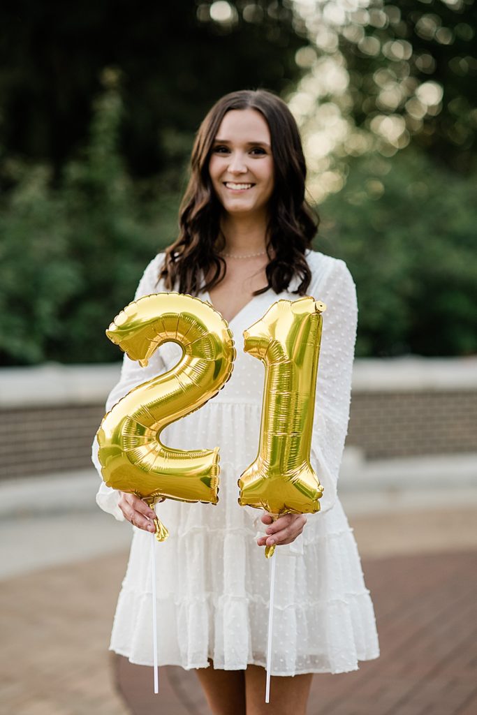 Michigan State graduation pictures on north campus in the fall with a white dress and balloons that say 21 for a 21st birthday by Allie & Co. Photography, East Lansing photographers