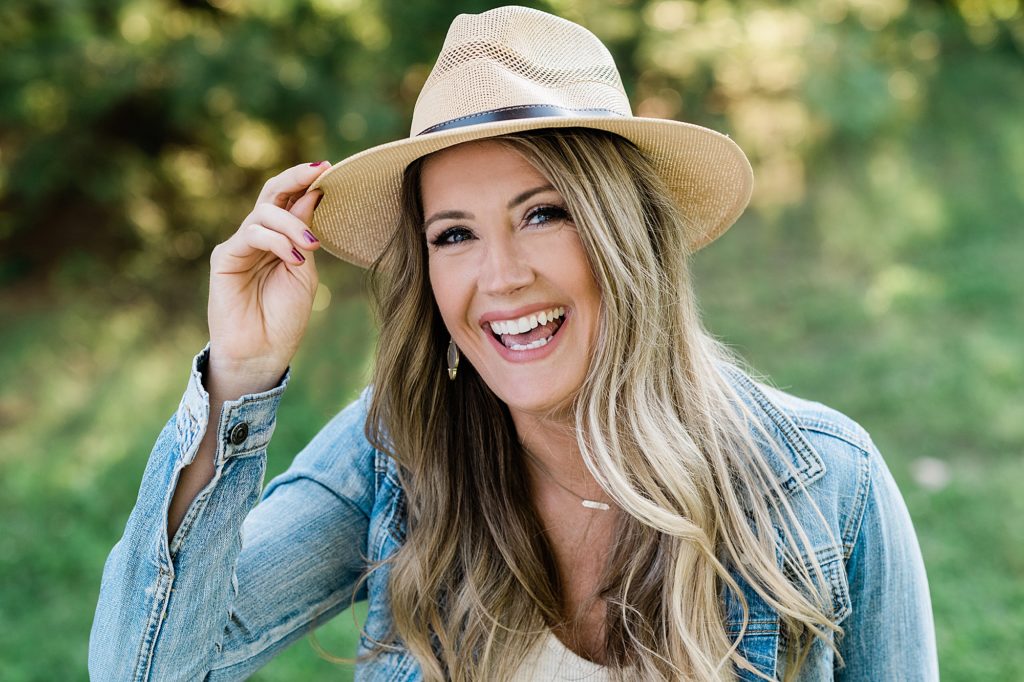 Lansing headshot photographer, photo of a woman laughing at the camera and touching her summer hat, by Allie Siarto & Co. Photography, Michigan branding photographers