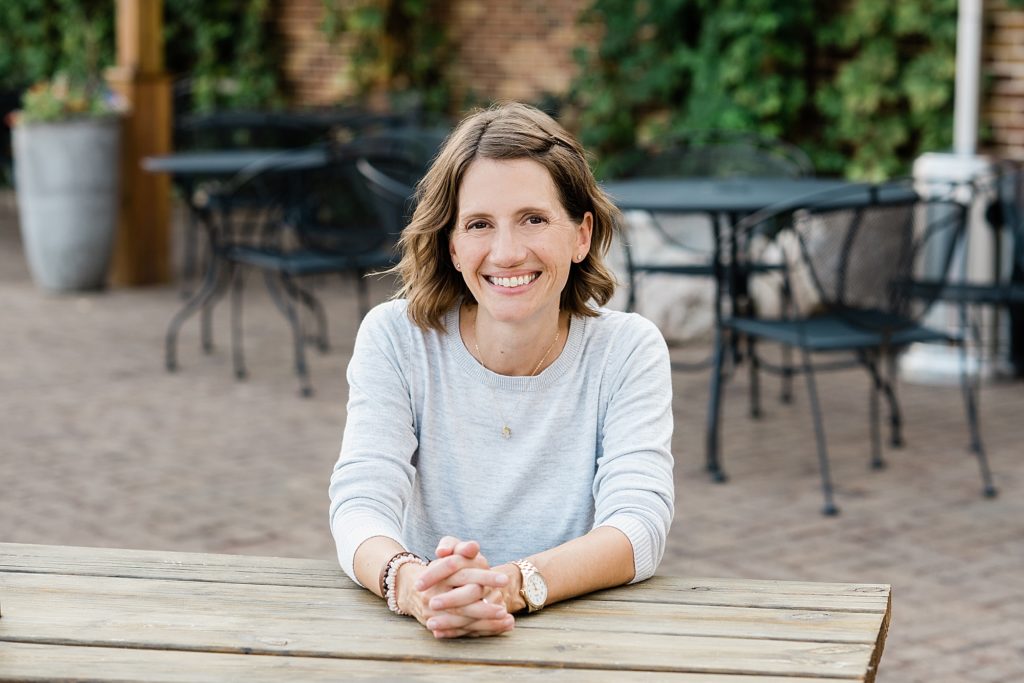 Lansing head shot photographer, photo of a woman sitting at a picnic table on an outdoor patio, by Allie Siarto & Co. Photography, Michigan branding photographers