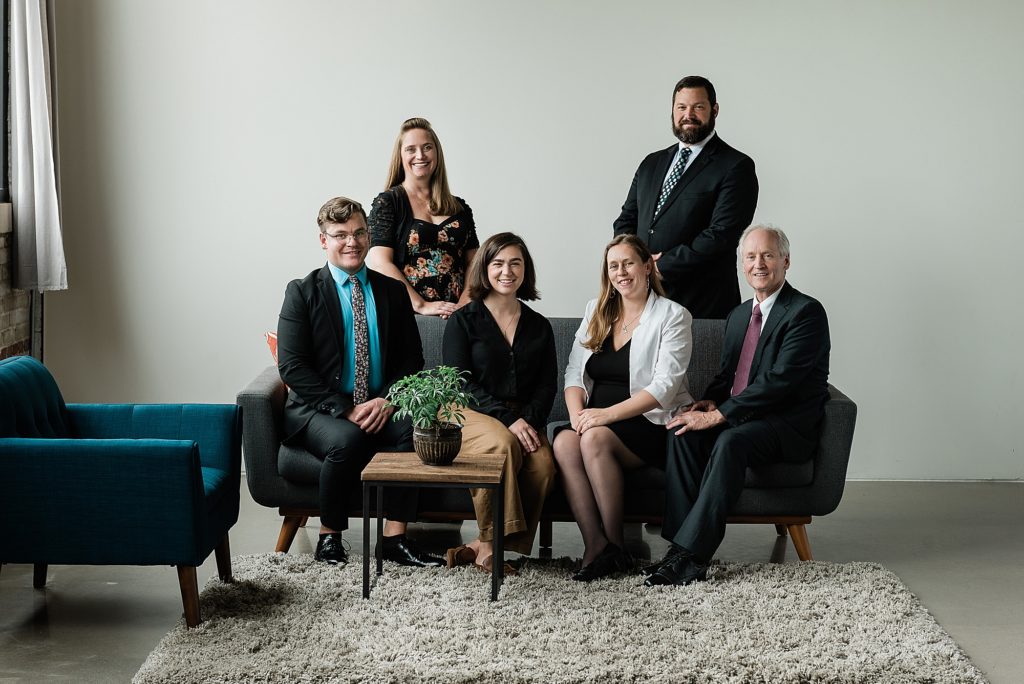 Lansing head shot photographer, photo of a team of realtors sitting on and around a gray couch, by Allie Siarto & Co. Photography, Michigan branding photographers