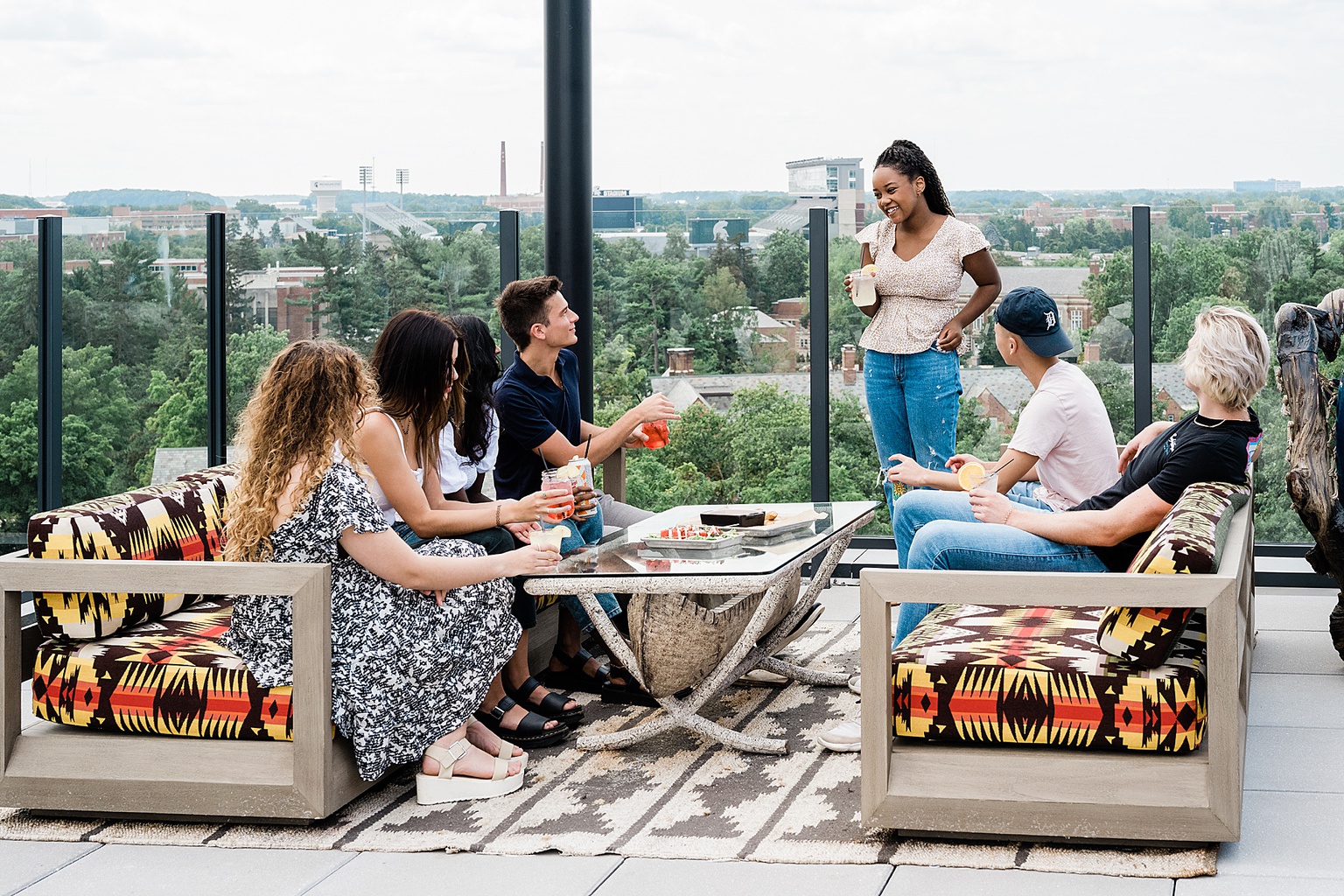 Graduate Rock bar commercial photography showing the rooftop bar with college students enjoying drinks together, overlooking Spartan Stadium and the Michigan State campus, by Allie Siarto & Co. Photography, Lansing, Michigan commercial photographers