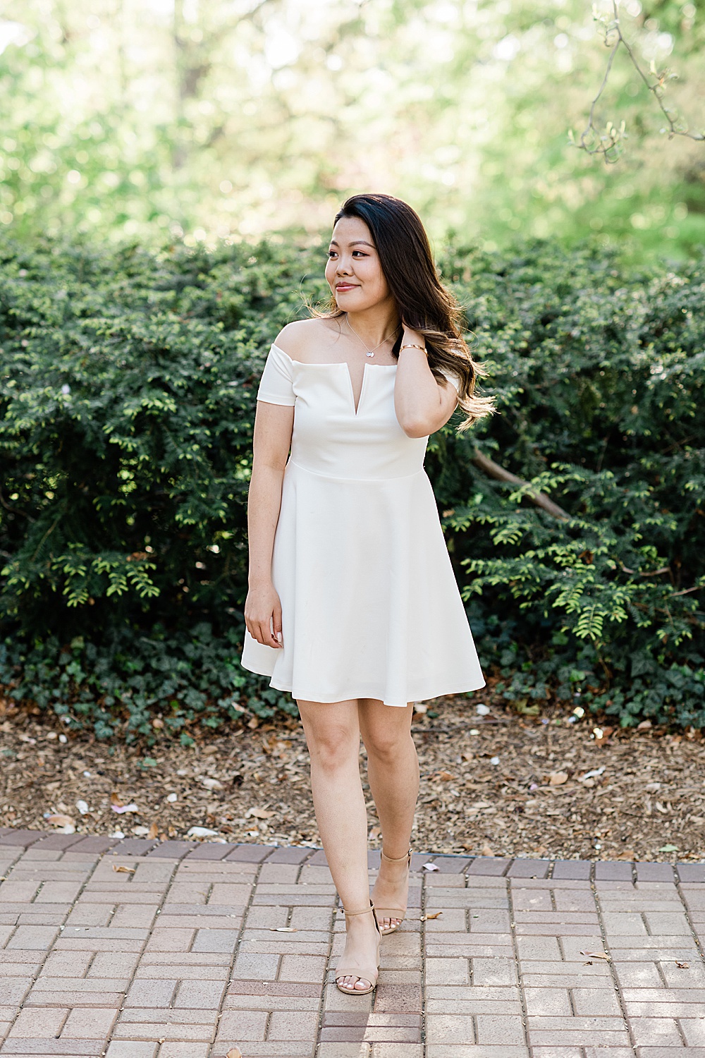 Michigan State Senior grad photoshoot on MSU's campus, photo of a woman in a white dress with a golden glow and greenery in the background, by Allie Siarto & Co., East Lansing photographers