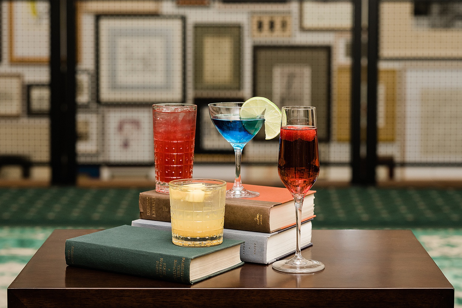 East Lansing's Graduate Hotel School Spirits Dinner, photo of all drinks lined up on a stack of books, by Allie Siarto & Co. Photography, Lansing commercial photographer