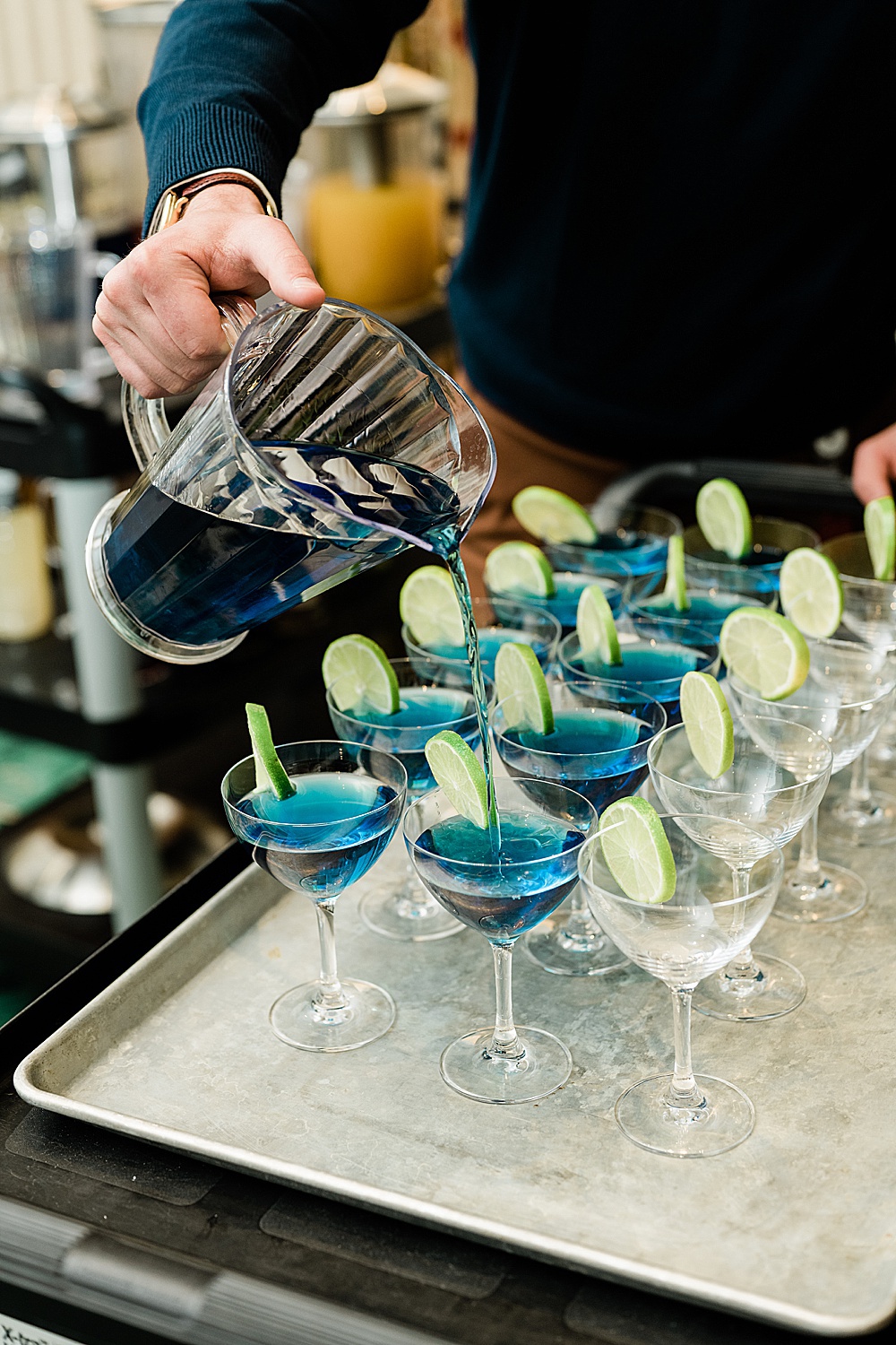 East Lansing's Graduate Hotel School Spirits Dinner, close up photo a man pouring blue drinks into martini glasses, by Allie Siarto & Co. Photography, Lansing commercial photographer