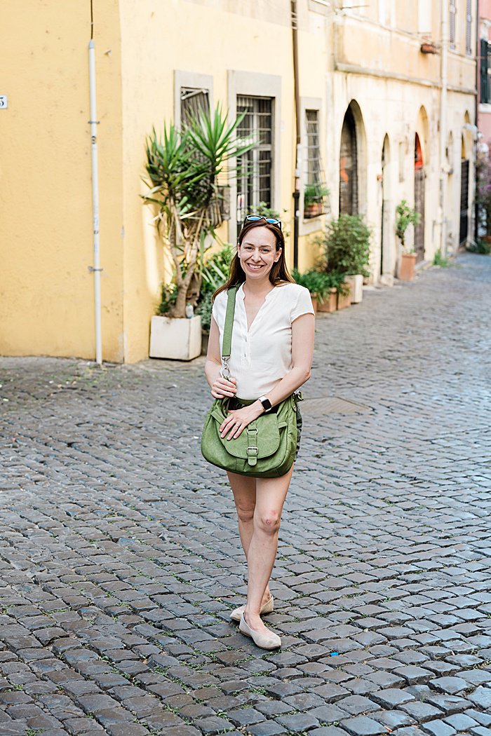 Michigan branding photographer in Rome - Allie on a cobblestone street in Trastevere with a yellow building behind