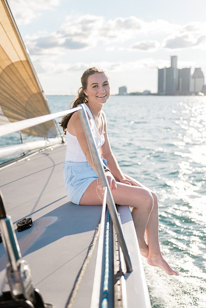 Detroit, Michigan headshot branding photos of a young photographer sitting on a sailboat smiling at the camera, surround by the Detroit River