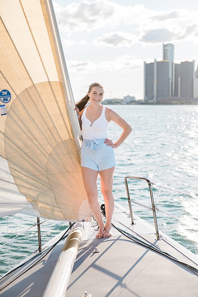 Detroit, Michigan headshot branding photos of a young photographer standing by the sail on a sailboat smiling and surrounded by the Detroit River - by Allie Siarto & Co. Photography, Michigan commercial photographers