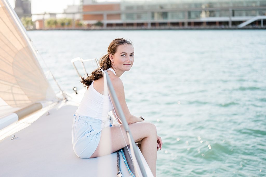 Detroit, Michigan headshot branding photos of a young photographer sitting on a sailboat and smiling at the camera, surrounded by the Detroit River - by Allie Siarto & Co. Photography, Michigan commercial and editorial photographers
