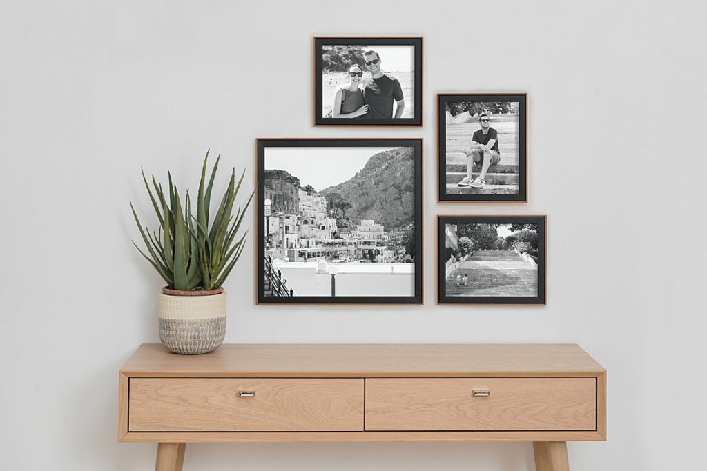Product photo of a set of black and wood frames hung in a frame gallery on the wall above a wooden desk by Allie Siarto Photography, East Lansing, Michigan product photographers