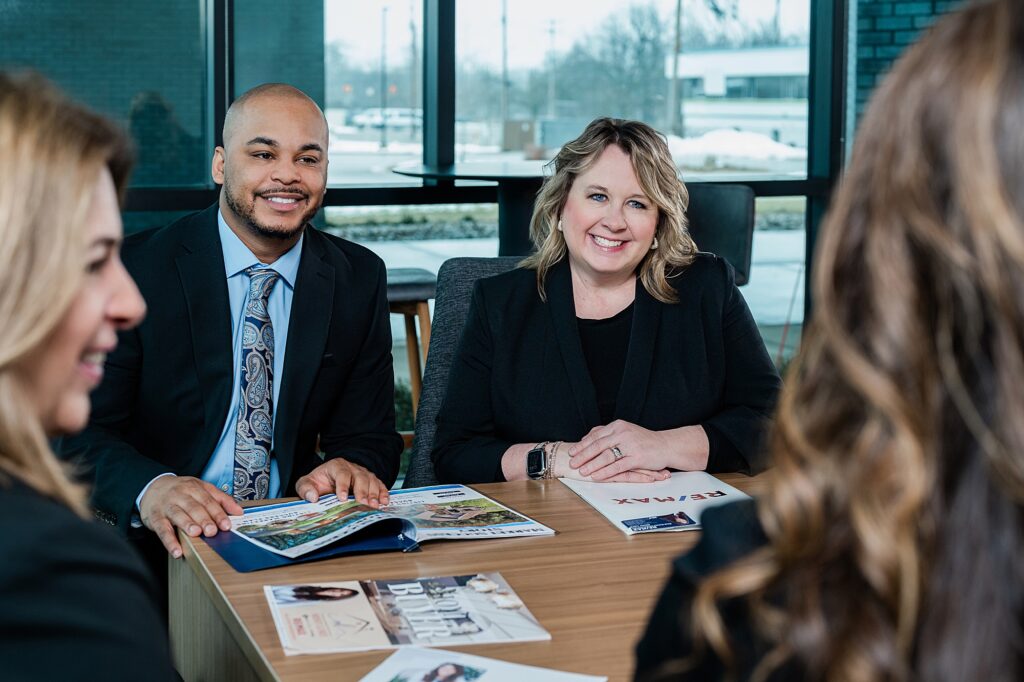 Marketing photos for a team of Lansing realtors, by Allie Siarto Photography, Lansing headshot and branding photographer; a photo of four realtors working together around a table