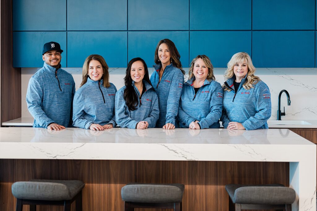 Marketing photos for a team of Lansing realtors, by Allie Siarto Photography, Lansing headshot and branding photographer; a photo of six realtors standing together in a kitchen