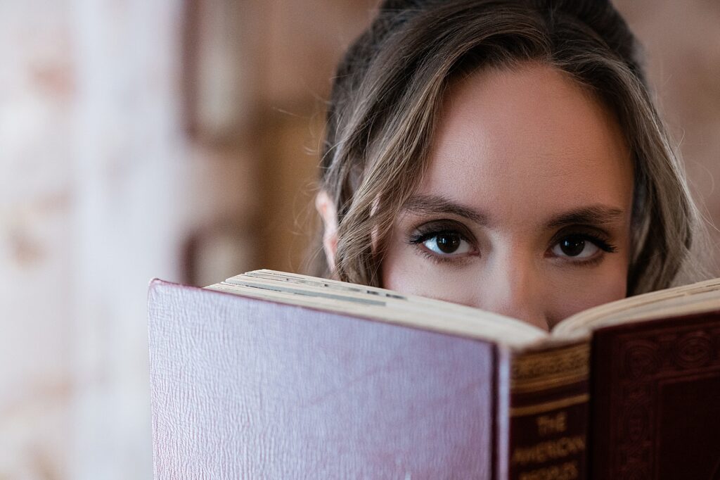 Creative business headshot: Audio book narrator Bridgerton inspired headshots by Allie Siarto Photography, headshot and portrait photographer out of East Lansing, Michigan - an audiobook narrator peeks over a vintage book